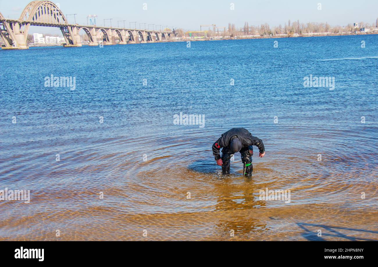 Dnepropetrovsk, Ukraine, Fluss Dnjepr - 02.21.2022: Professioneller Taucher in der Nähe der Flussküste. Kommerzielles Tauchen. Winter. Stockfoto