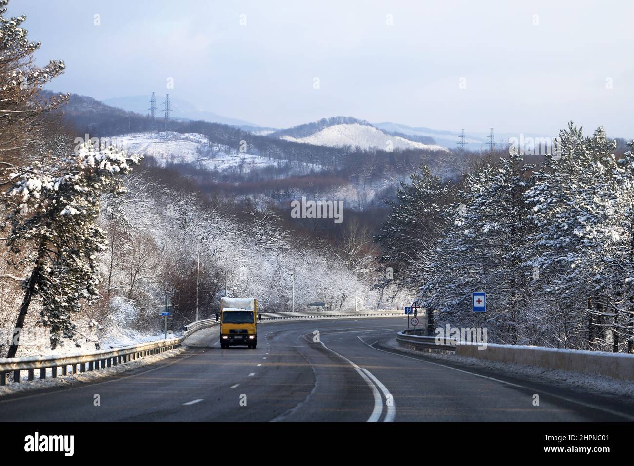 Schöne Winterbergstraße mit schneebedeckten Bäumen an der Seite der Straße Stockfoto