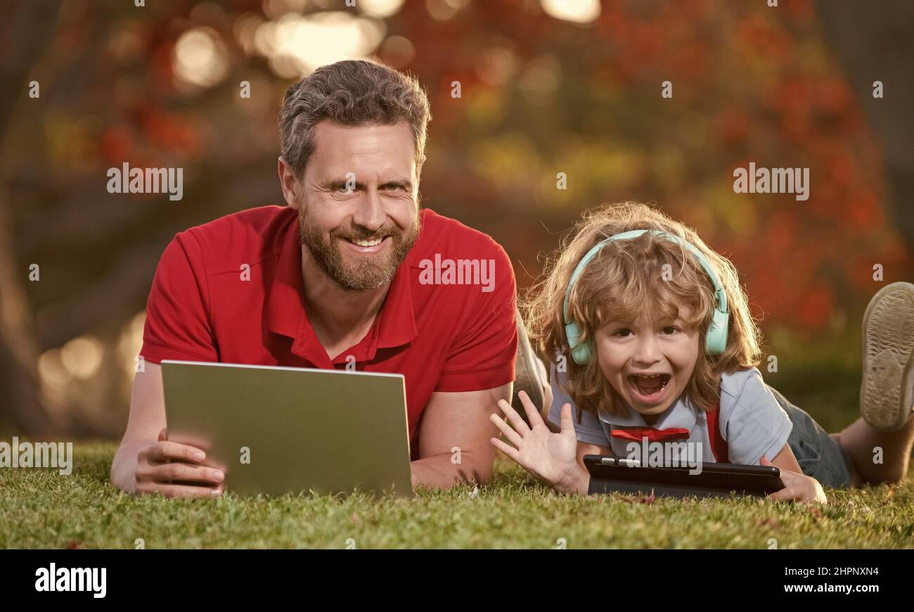 Vater und Sohn nutzen moderne Kommunikationstechnik im Park. Familienblogging Stockfoto