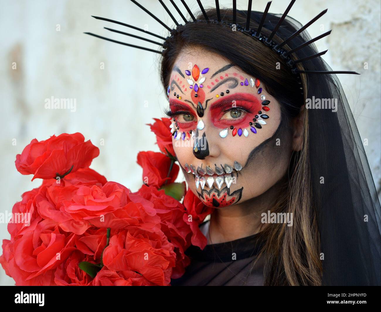 Junge schöne kaukasische Frau mit gruseliger traditioneller Gesichtsbemalung und Gesichtsbemalungen am mexikanischen Tag der Toten (Día de los Muertos) schaut den Betrachter an. Stockfoto