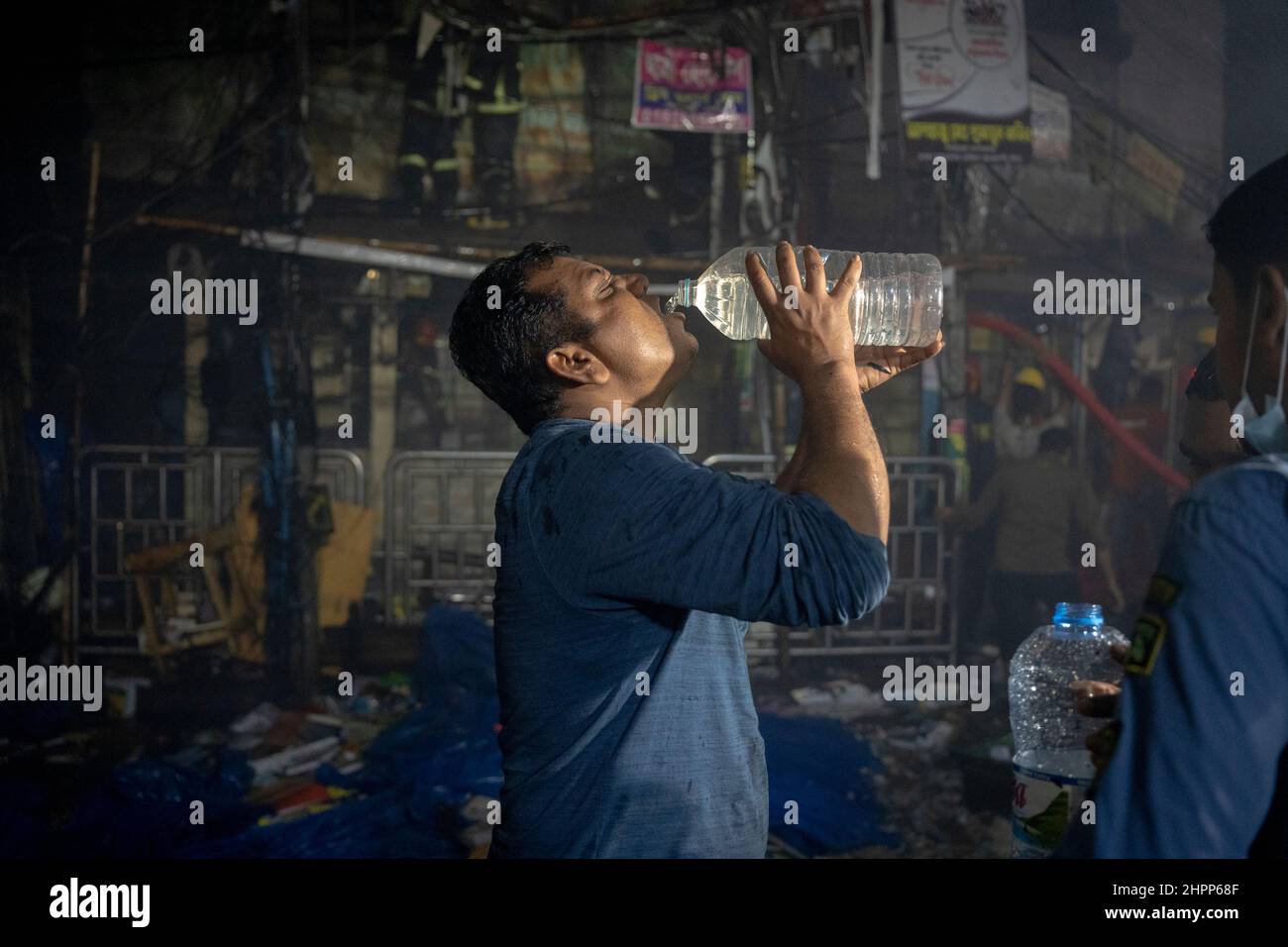 Dhaka, Bangladesch. 22nd. Februar 2022. Ein Freiwilliger trinkt Wasser, nachdem er Zeit in der Nähe des Feuers verbracht hat.Auf dem Nilkhet-Buchmarkt, dem größten Buchmarkt, brach ein Feuer aus. Das Feuer entbrannte rund 25 Buchhandlungen, was zu Tausenden von verbrannten Büchern führte. Die Feuerwehrleute haben das Feuer nach etwa einer Stunde übergossen. (Bild: © Rizwan Hasan/Pacific Press via ZUMA Press Wire) Stockfoto