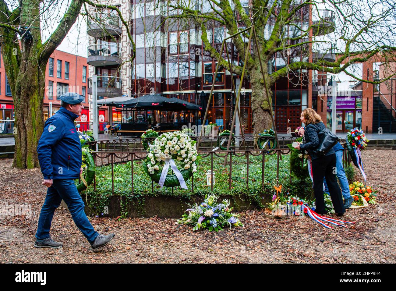 Während der Gedenkfeier wird ein Militärveteran dabei gesehen, wie er bei einem der Blumenkranze in der Nähe hilft. Die Bombardierung von Nijmegen war ein ungeplanter Bombenangriff amerikanischer Flugzeuge auf die Stadt Nijmegen in den Niederlanden am 22. Februar 1944. Bei diesem alliierten Fehlschlag wurden fast 800 Menschen getötet und ein großer Teil des Stadtzentrums von Nijmegen wurde zerstört. Jeden 22nd. Februar findet im Raadhuishof, dem Ort, an dem sich die Montessori-Schule befand, eine offizielle Gedenkfeier statt, an der 24 Kinder und 8 Schwestern getötet wurden. Es gibt ein Denkmal namens 'De Schommel' wh Stockfoto