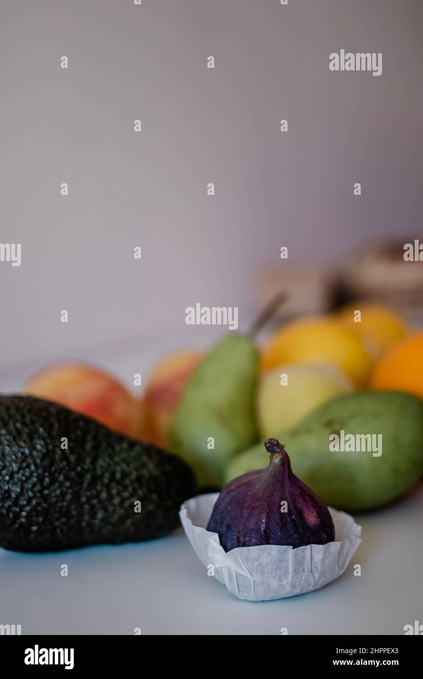 Frische Feige im Vordergrund mit anderen Früchten auf hellem Hintergrund auf dem Tisch Stockfoto