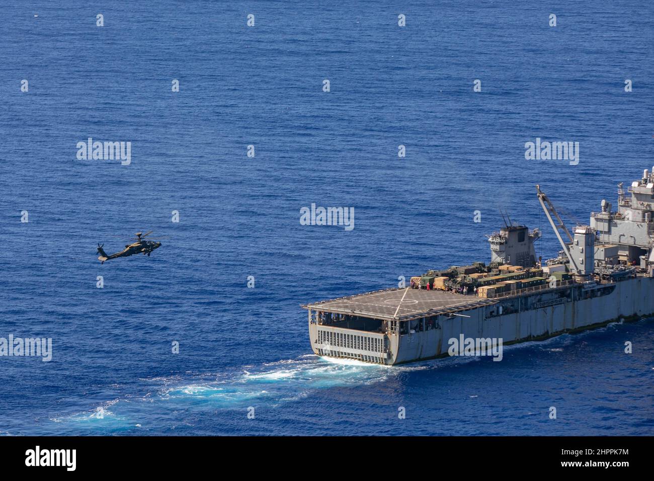 US-Armee Boeing AH-64 Apache-Hubschrauber bereitet sich auf die Landung an Bord der USS Pearl Harbor im Pazifischen Ozean vor der Küste von Oahu vor, 18. Februar 2022. Die gemeinsame Serviceschulung war Teil einer Qualifikation für die Landung von Deck, die durchgeführt wurde, um die Fähigkeiten zur Unterstützung von Seemissionen in der Indo-Pazifik-Region zu erhalten. (USA Armeefoto von SGT Carlie Lopez/28th Public Affairs Detachment.) Stockfoto