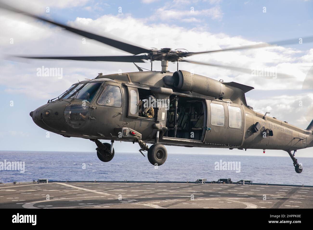 US Army UH-60m Black Hawk Hubschrauber bereitet sich auf die Landung an Bord der USS Pearl Harbor im Pazifischen Ozean vor der Küste von Oahu vor, 18. Februar 2022. Die gemeinsame Serviceschulung war Teil einer Qualifikation für die Landung von Deck, die durchgeführt wurde, um die Fähigkeiten zur Unterstützung von Seemissionen in der Indo-Pazifik-Region zu erhalten. (USA Armeefoto von SGT Carlie Lopez/28th Public Affairs Detachment.) Stockfoto