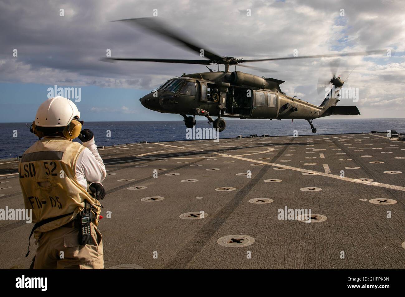 Ein US Army UH-60m Black Hawk fliegt am 18. Februar 2022 im Pazifischen Ozean als Teil des Trainings über die USS Pearl Harbor. Die gemeinsame Serviceschulung war Teil einer Qualifikation für die Landung von Deck, die durchgeführt wurde, um die Fähigkeiten zur Unterstützung von Seemissionen in der Indo-Pazifik-Region zu erhalten. (USA Armeefoto von SGT Carlie Lopez/28th Public Affairs Detachment.) Stockfoto