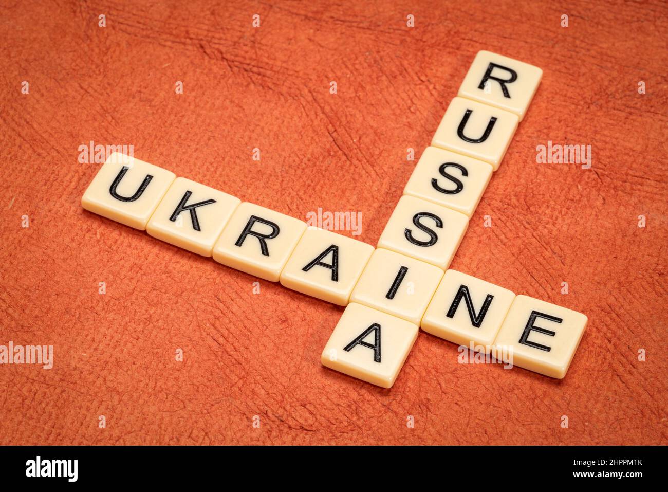 Kreuzworträtsel der Ukraine und Russlands in Elfenbein-Buchstabenkacheln gegen strukturiertes handgefertigtes Papier Stockfoto