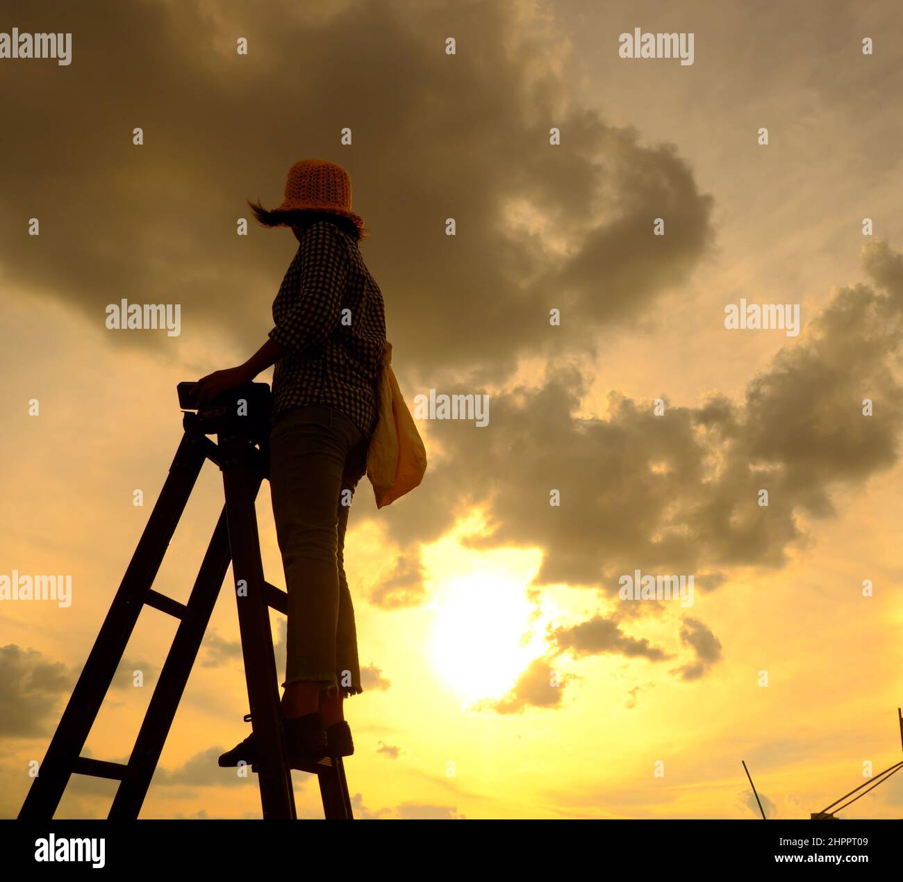 Erstaunliche Szene von vietnamesischen Frau, wenn zu Hause bleiben durch soziale Distanzierung, sie machen Spaß beim Sonnenuntergang auf dem Dach durch Stand auf Leiter, wenn die Sonne auf m untergehen Stockfoto