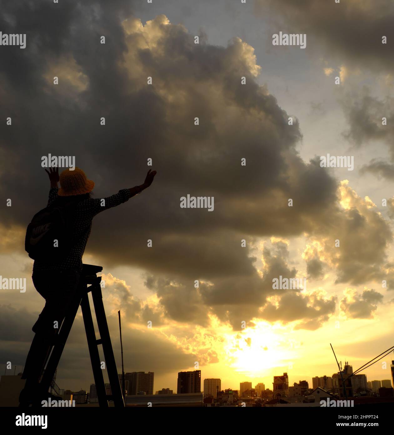 Erstaunliche Szene von vietnamesischen Frau, wenn zu Hause bleiben durch soziale Distanzierung, sie machen Spaß beim Sonnenuntergang auf dem Dach durch Stand auf Leiter, wenn die Sonne auf m untergehen Stockfoto