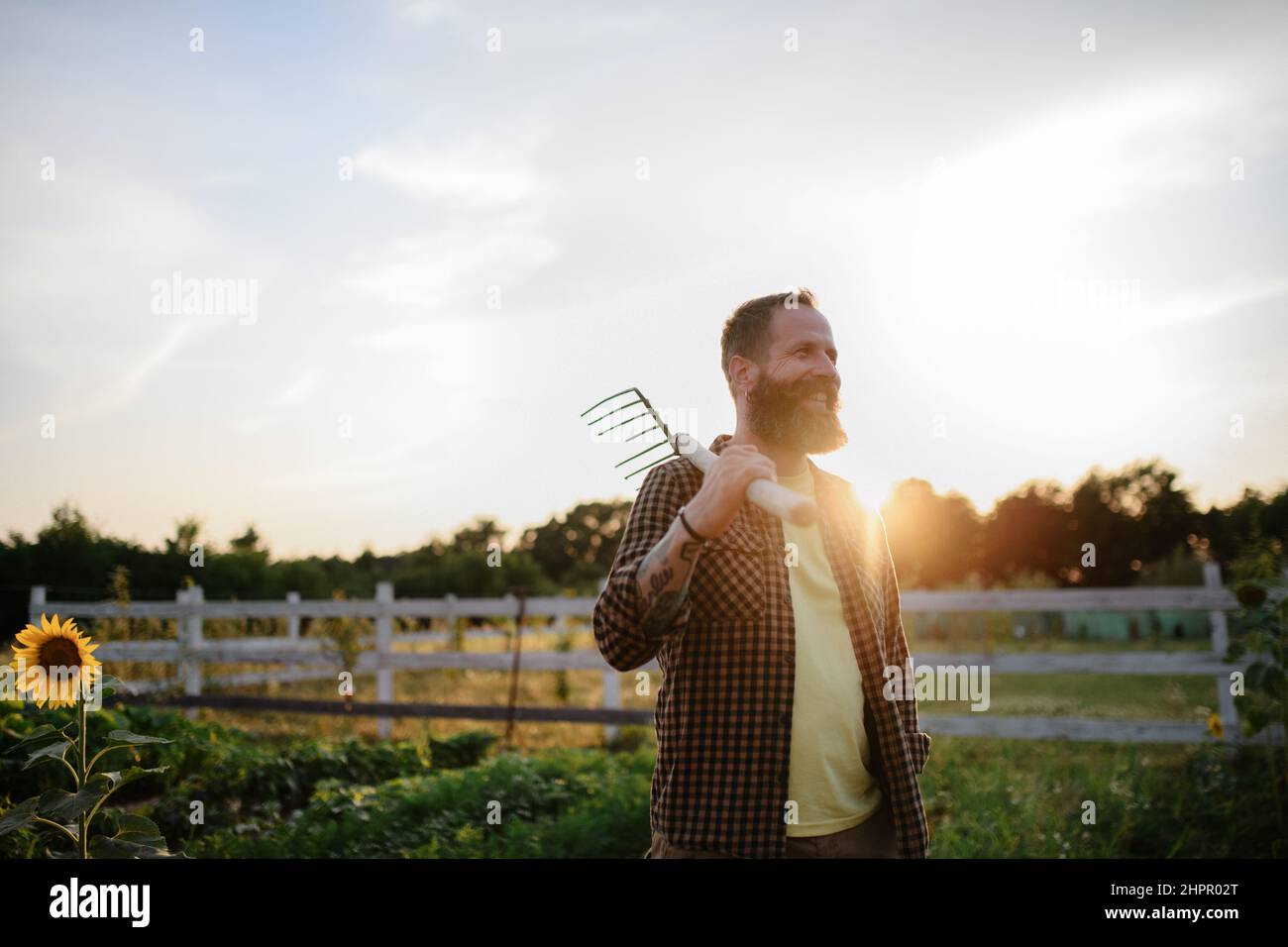 Glücklicher reifer Bauer Mann mit Gartenwerkzeug im Freien auf dem Feld. Stockfoto