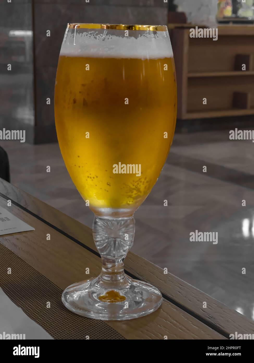 Ein frisches Glas gekühltes Bier wird auf einem Tisch serviert. Nahaufnahme. Stockfoto