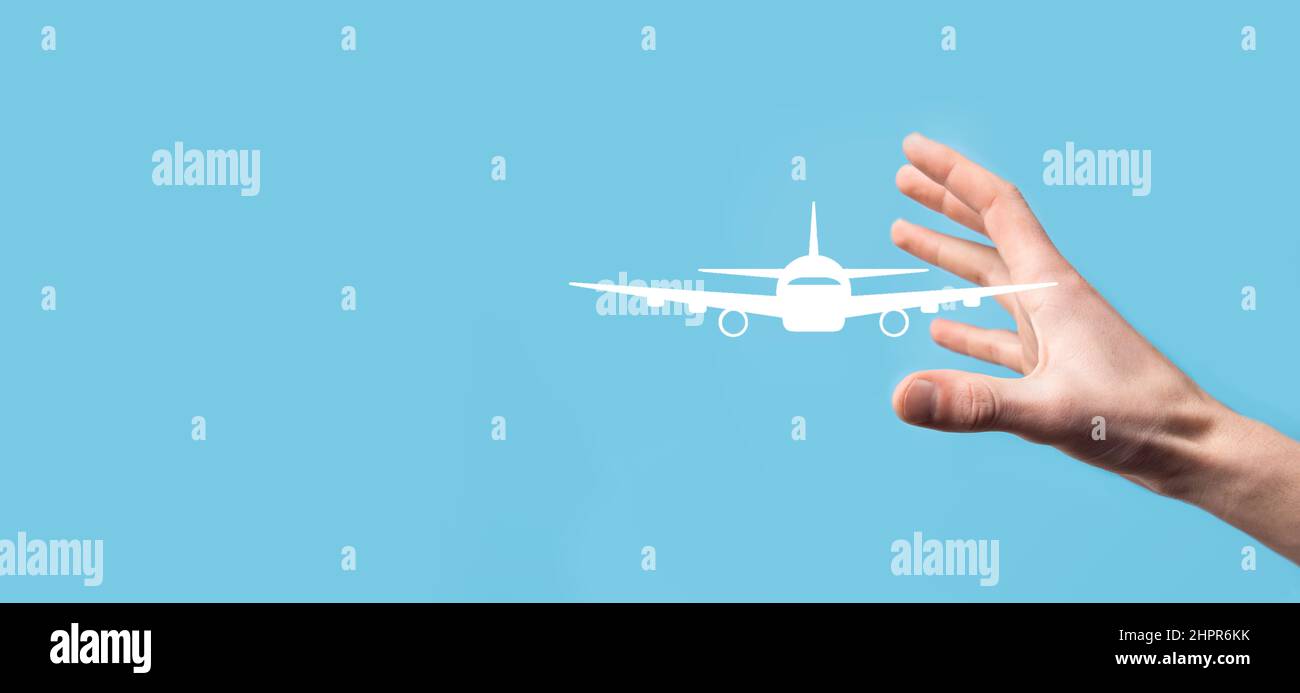 Männliche Hand hält Flugzeug-Symbol auf blauem Hintergrund. Banner.nline Ticketkauf.Reise-Icons über Reiseplanung, Transport, Hotel, Flig Stockfoto