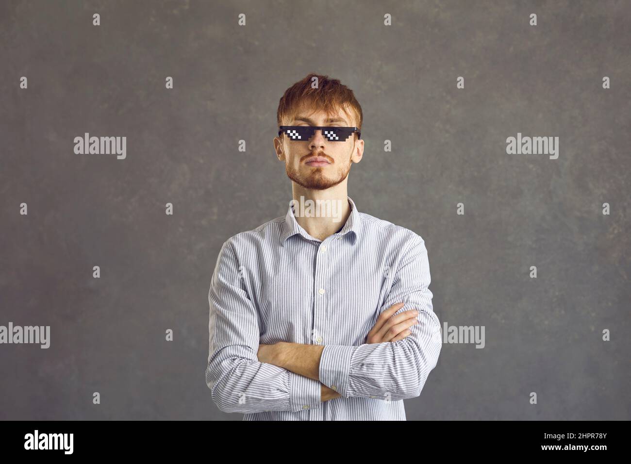 Hochmütiger bärtiger Filmfan mit Pixelbrille, Person mit Kreuz auf den Armen Stockfoto