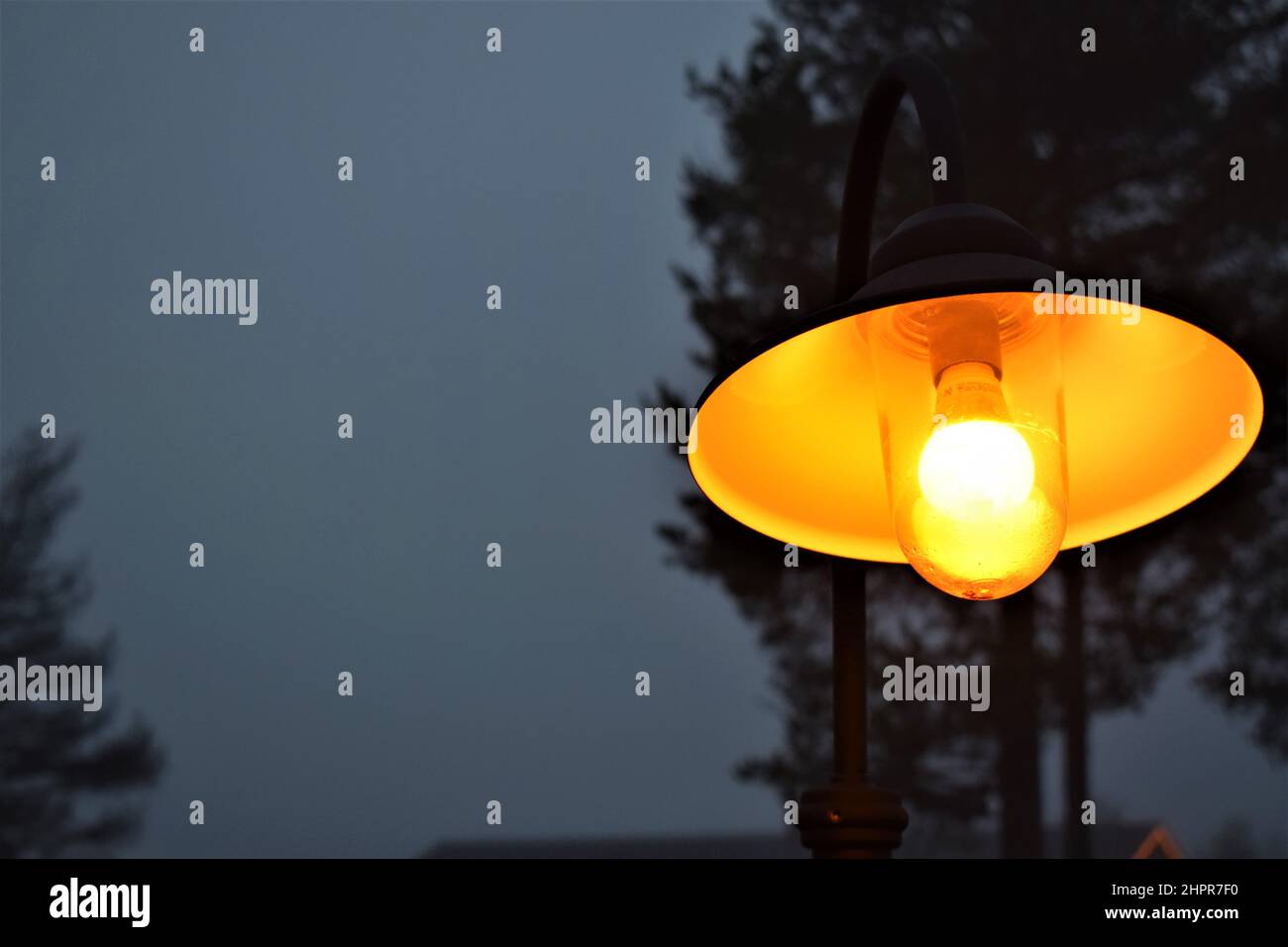 Leuchtend gelbe Lampe im Nebel. Nahaufnahme. Hell im Dunkeln. Herbstabend. Lappland, Finnland Stockfoto