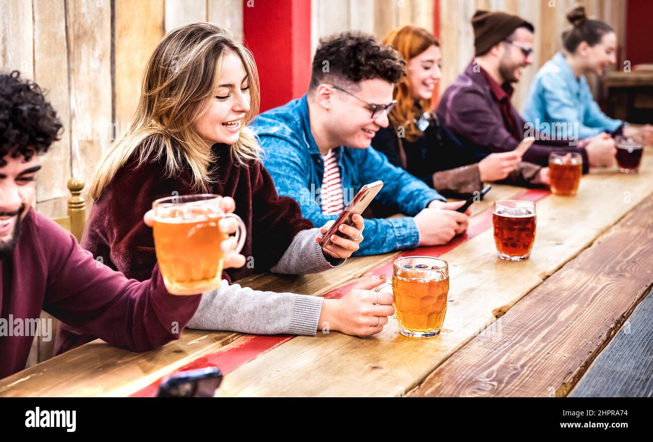Fröhliche, süchtig machende Freunde trinken Bier und haben Spaß mit mobilen Smartphones im Brauereigasthaus - Life Style Konzept mit Millionenleuten teilhaben Stockfoto