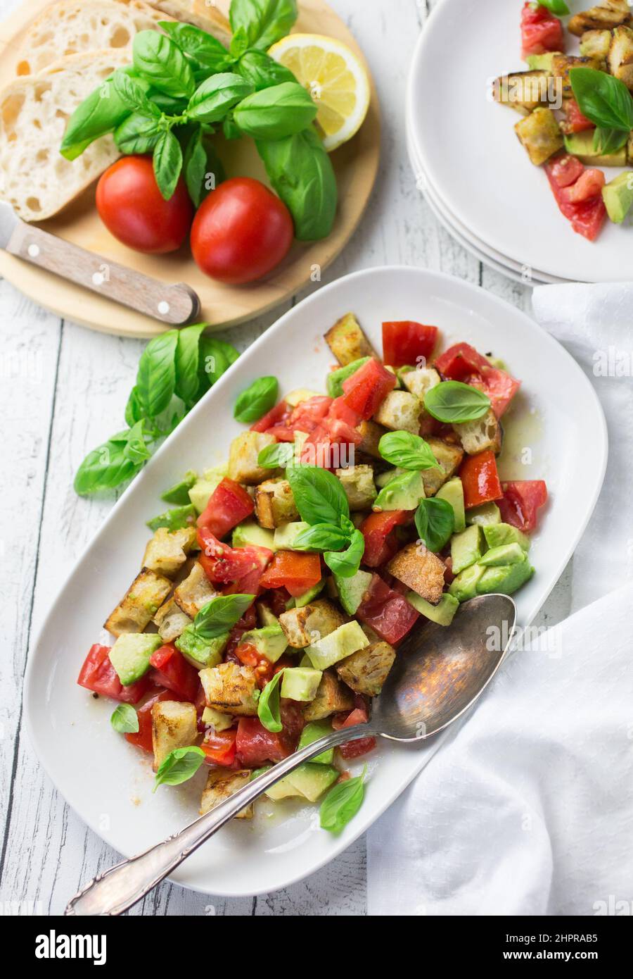 Ein großer weißer Teller voller italienischer Panzanella-Salat mit Tomaten, Brot, Avocado und Basilikum Stockfoto