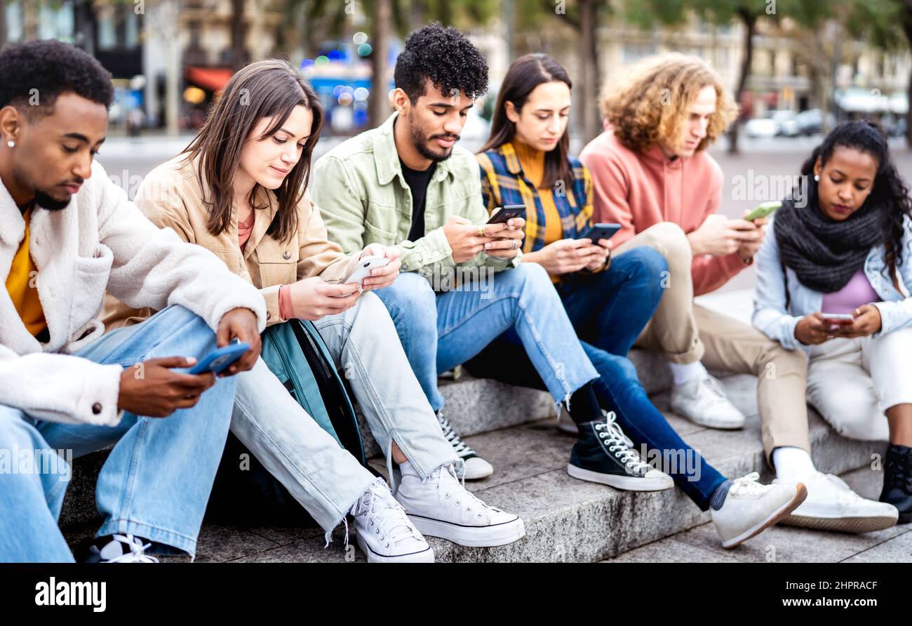 Gelangweilte Freunde Gruppe mit Handy sitzen auf dem Universitätshochschulhof - Junge Menschen süchtig nach Smartphone-Geräten - Technologie-Konzept wit Stockfoto