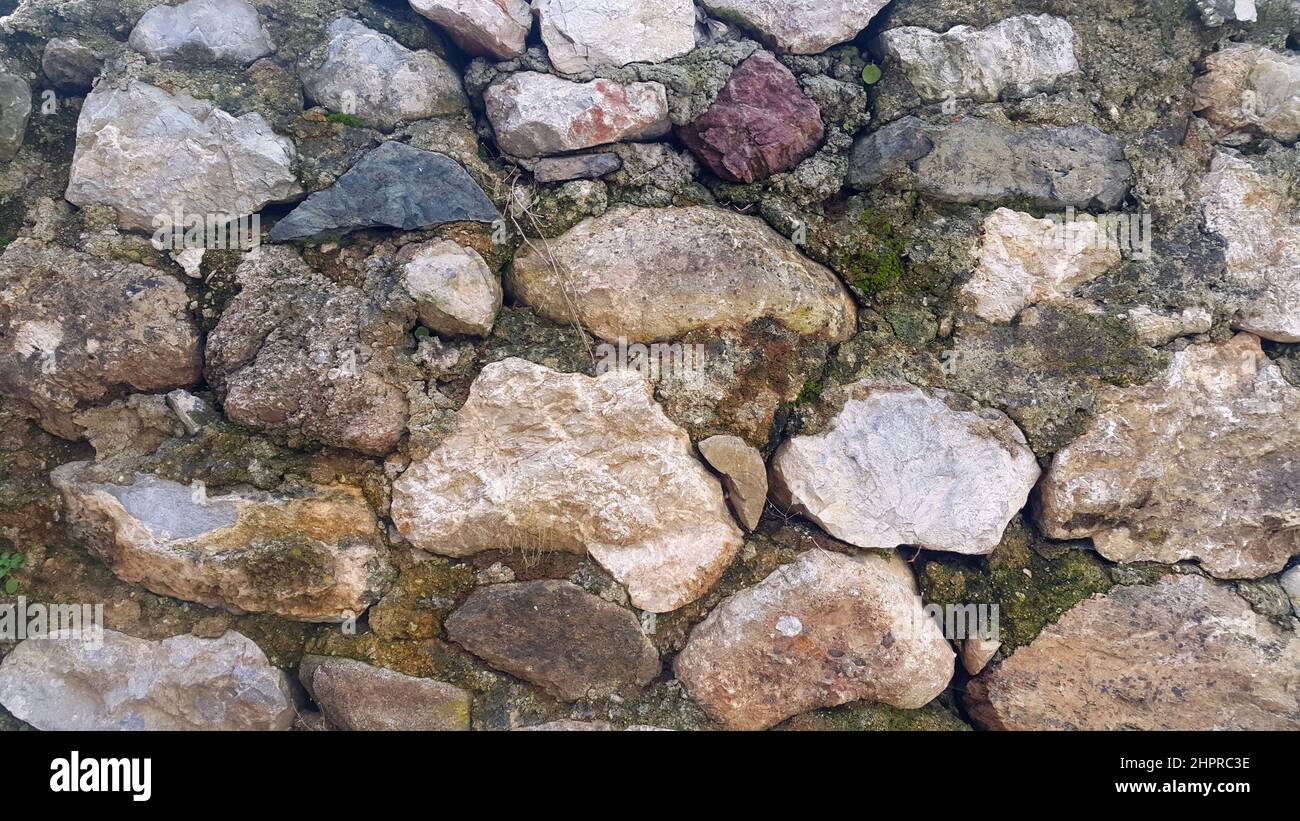 Traditionelle alte moosige Steinmauer. Vorderansicht und Nahaufnahme. Stockfoto