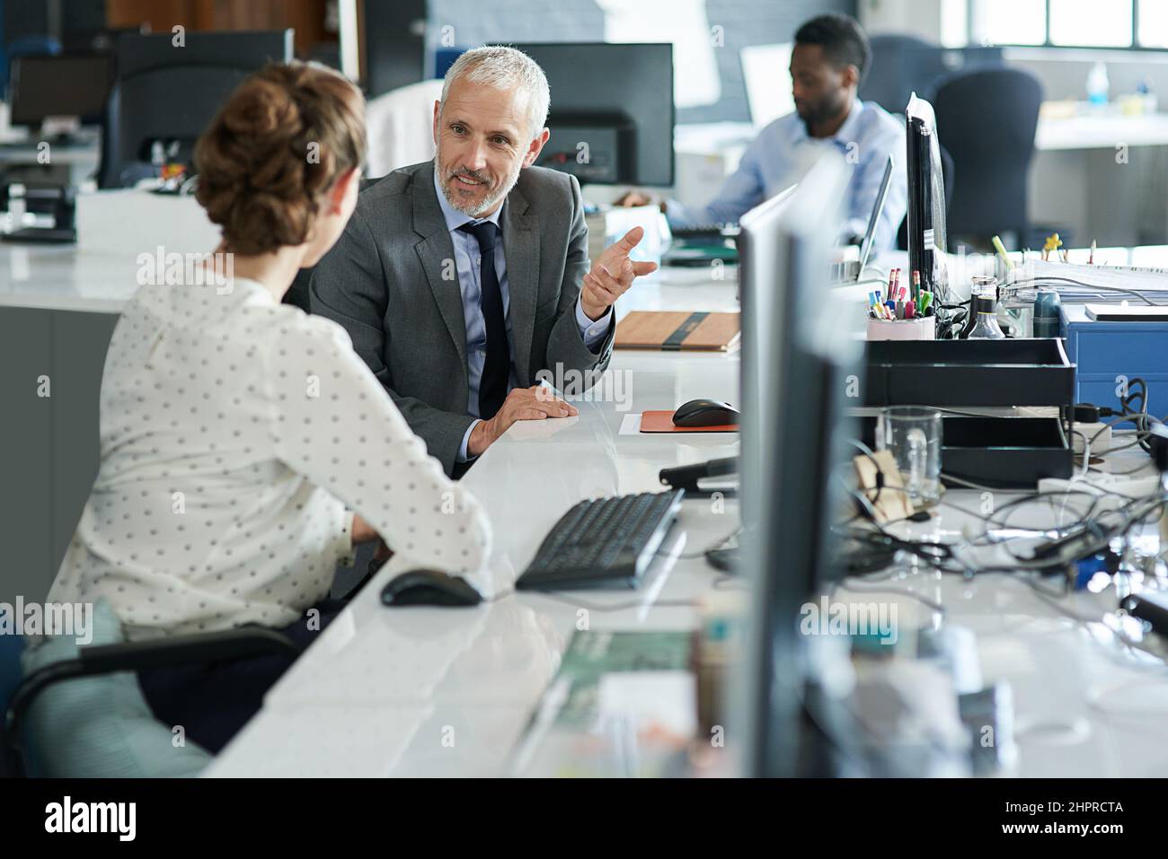 Die Leute, die Ideen haben. Aufnahme von zwei Kollegen, die an ihren Arbeitsplätzen sitzen und miteinander reden. Stockfoto
