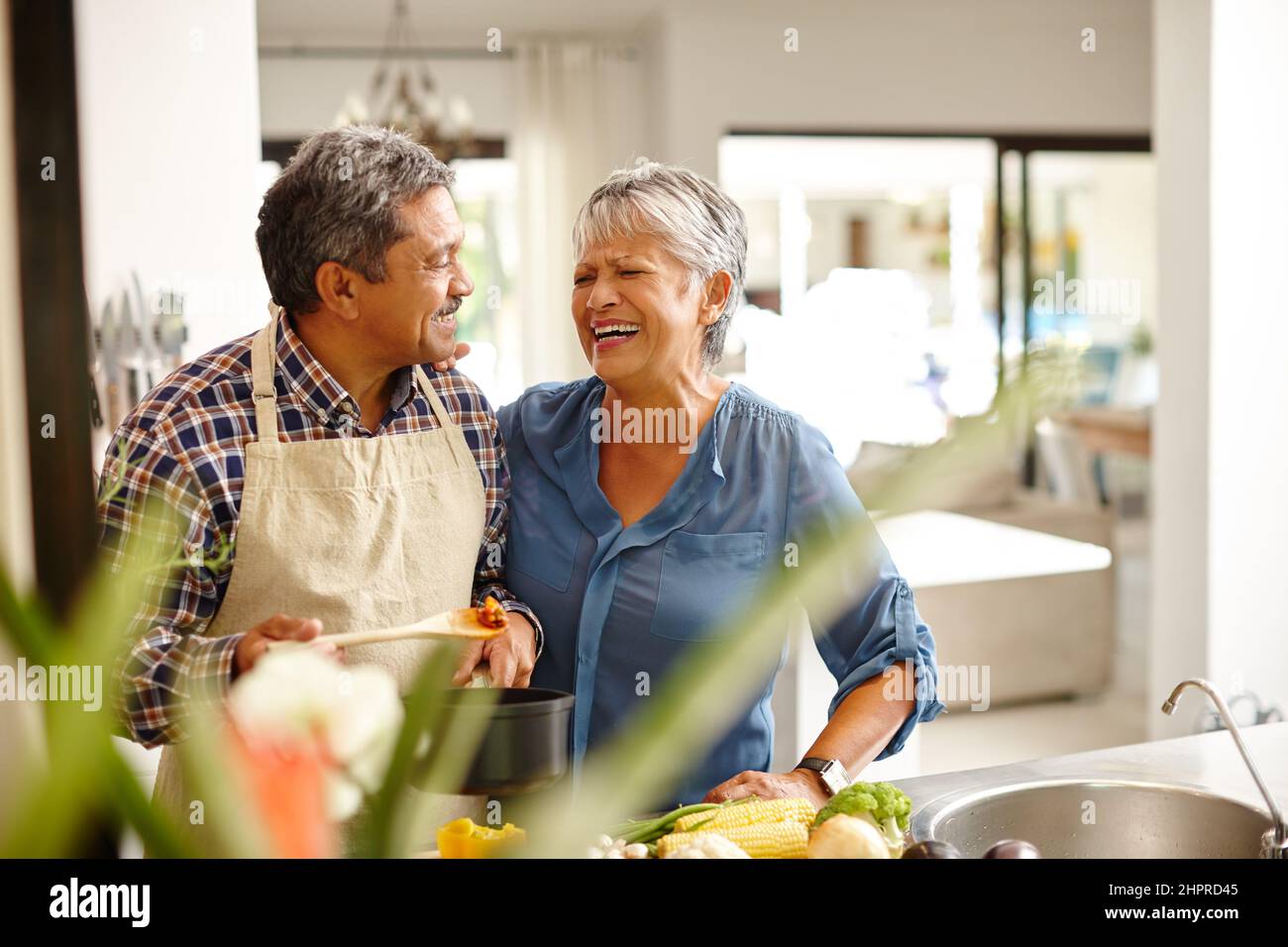 Viel Liebe in ihr Essen stecken. Aufnahme eines glücklichen Seniorenpaares, das zu Hause ein gesundes Essen kocht. Stockfoto