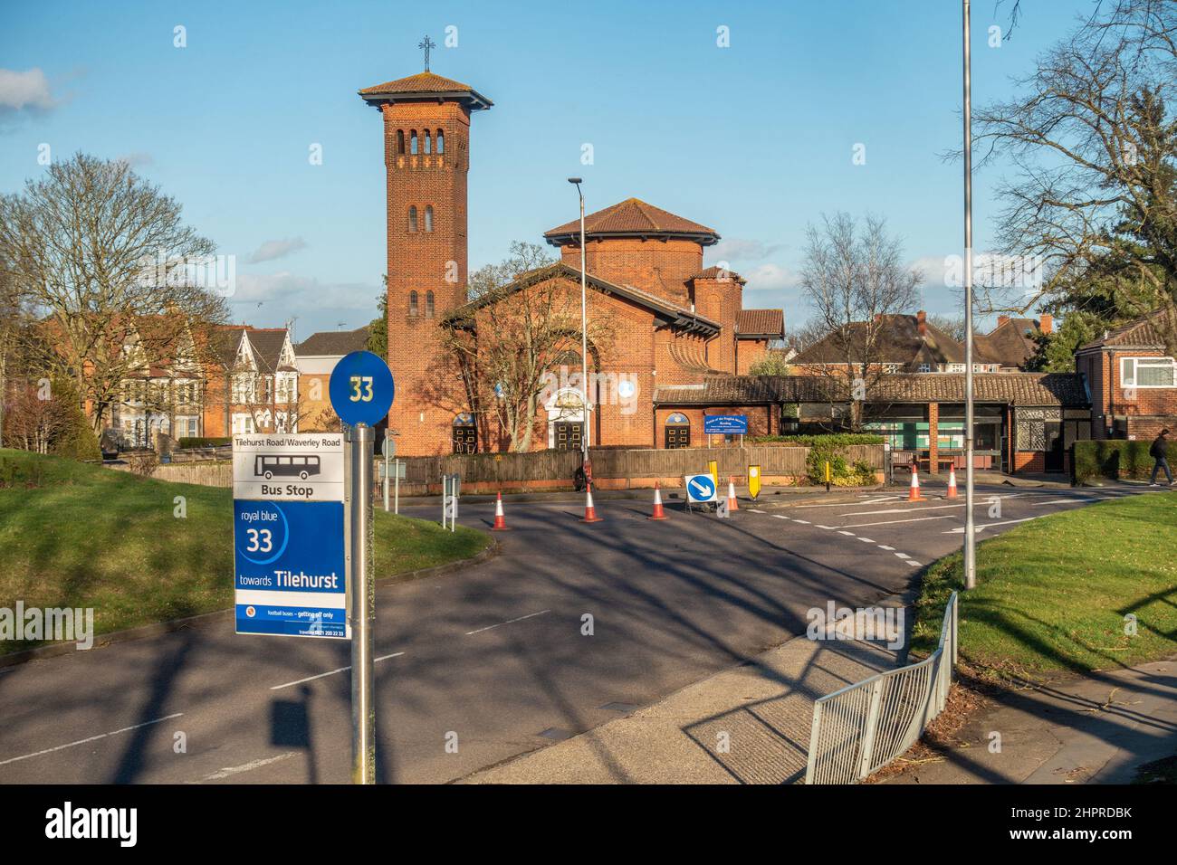 Bushaltestelle Nr. 33 vor der katholischen Kirche der englischen Märtyrer in Tilehurst, Reading, Großbritannien. Kegel und Straßenschilder im Hintergrund lenken den Verkehr ab. Stockfoto