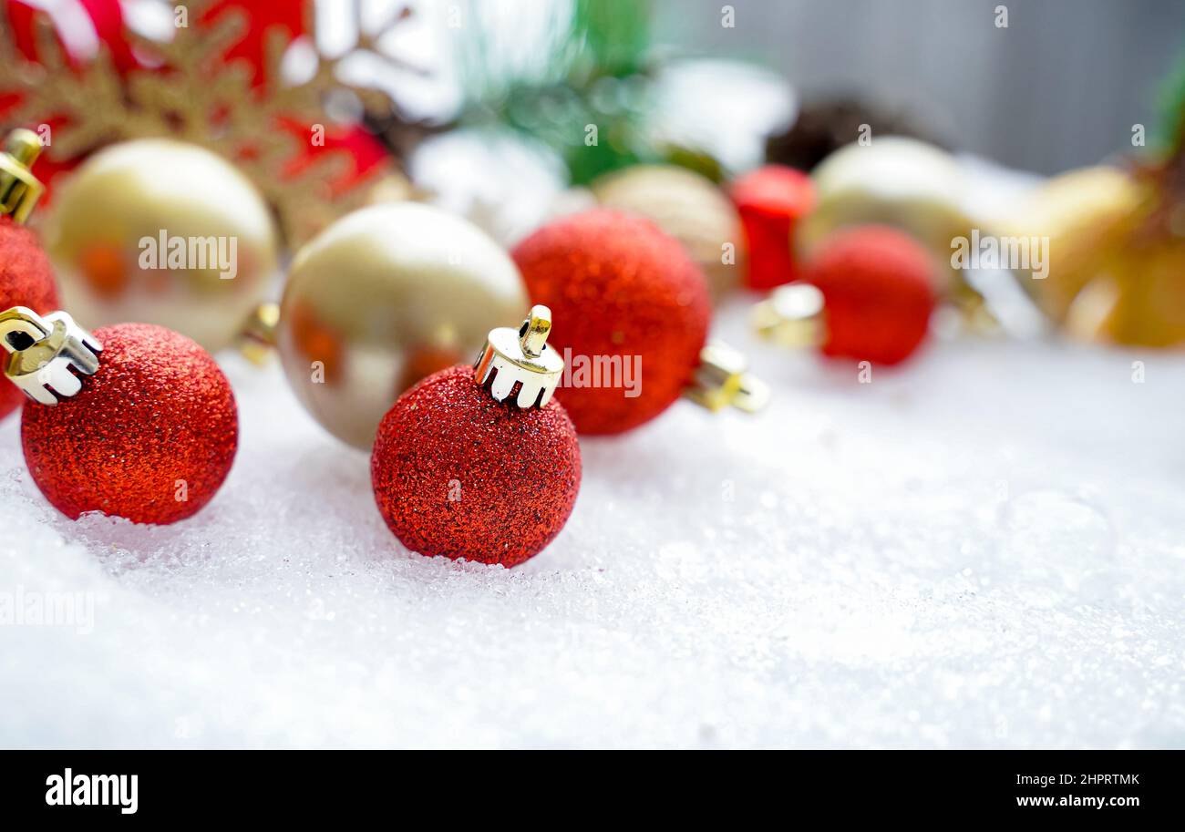 Weihnachten des Winters - Weihnachtskugeln mit Band auf Schnee, Winterurlaub Konzept. Weihnachtliche rote Kugeln, goldene Kugeln, Kiefer und Schneeflocken Dekoration Stockfoto