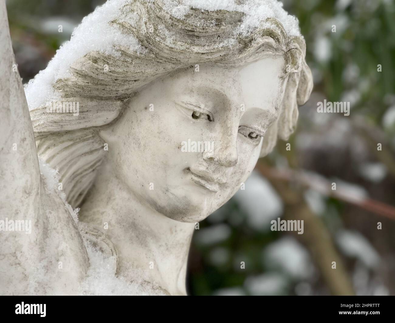 Das zarte Gesicht einer Frauenstatue mit Schnee Stockfoto