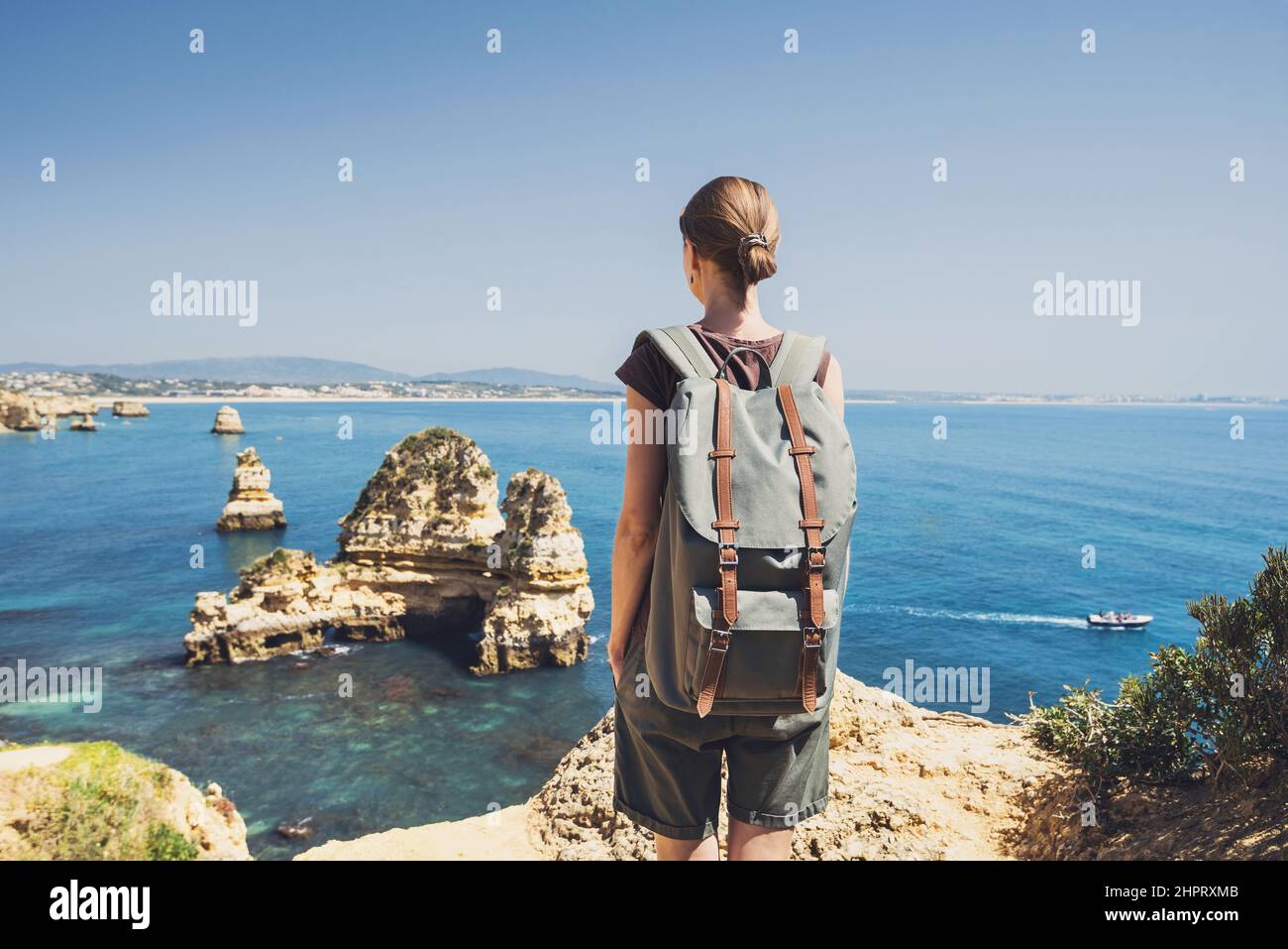 Junge Frau, die das Meer in Lagos Stadt, Algarve Region, Portugal betrachtet. Reise- und Active Lifestyle-Konzept Stockfoto