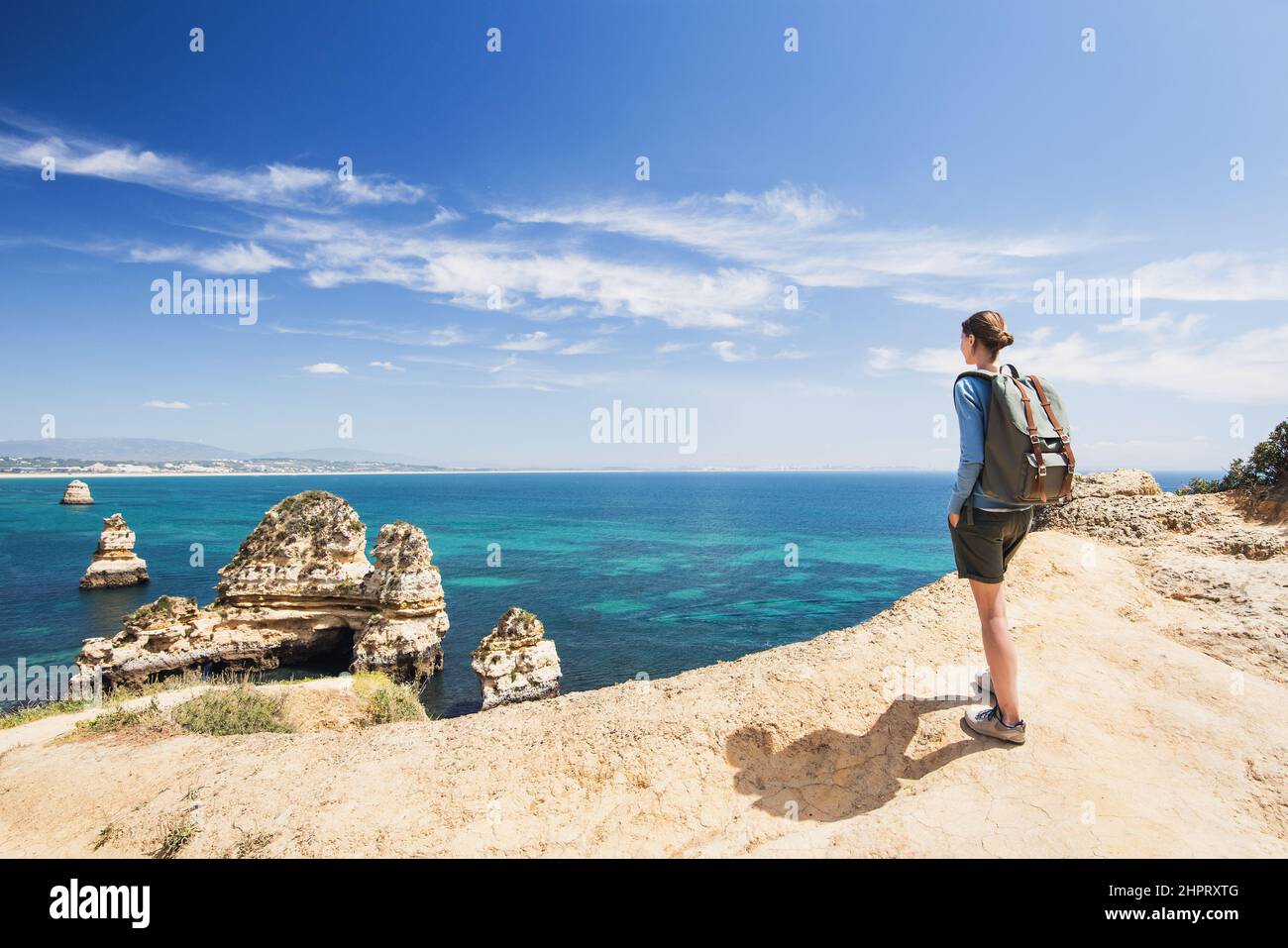 Junge Frau, die das Meer in Lagos Stadt, Algarve Region, Portugal betrachtet. Reise- und Active Lifestyle-Konzept Stockfoto