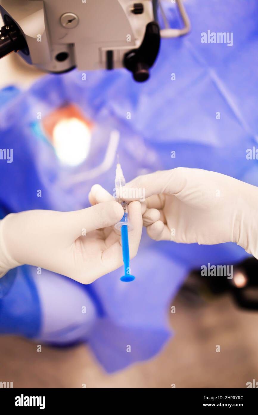 Detail einer Krankenschwester, die während der Operation eine Spritze an einen Chirurgen austeilt Stockfoto