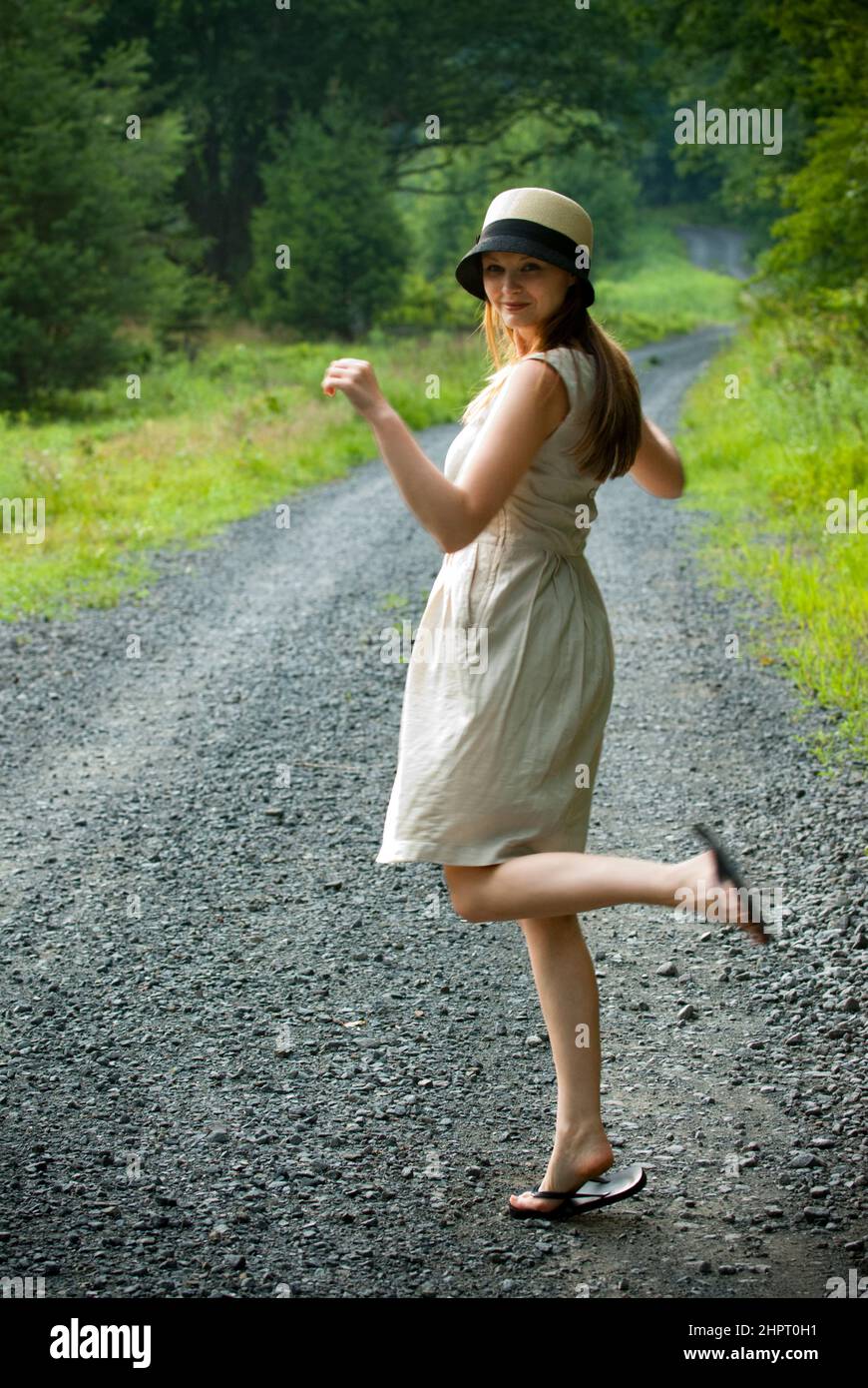 Eine junge Frau, die sich auf einer Schotterstraße die Fersen hochkickt Stockfoto