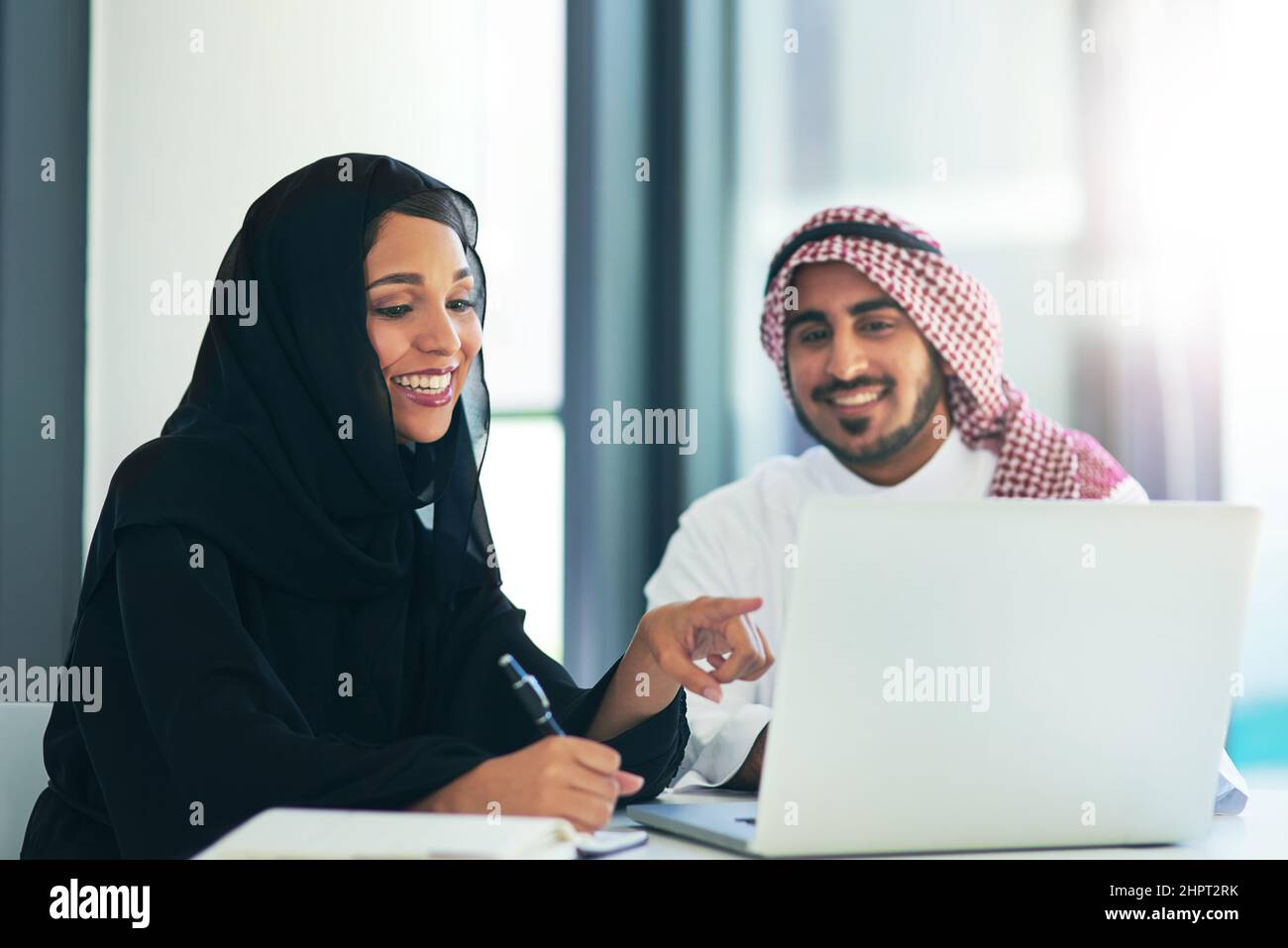 Gemeinsam den Traum des Teams zu verwirklichen. Aufnahme von zwei muslimischen Kollegen, die in einem modernen Büro einen Laptop zusammen benutzen. Stockfoto