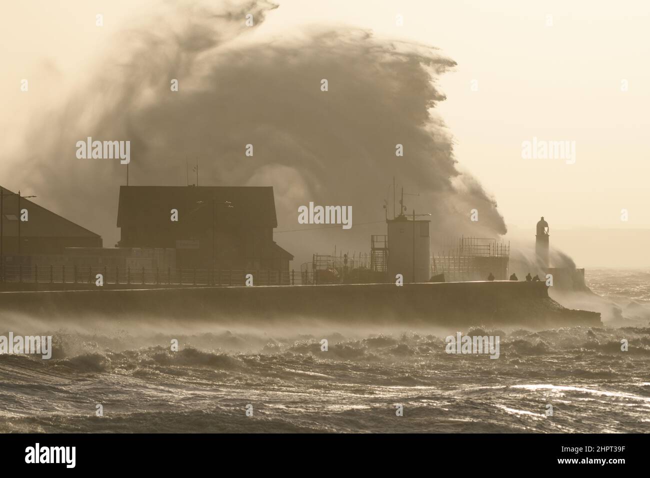 Porthcawl, South Wales, Großbritannien. 18. Februar 2022. Britisches Wetter: Große Wellen stürzen heute Morgen über die Verteidigung des Meeres, als der Sturm Eunice eintrifft. Stockfoto