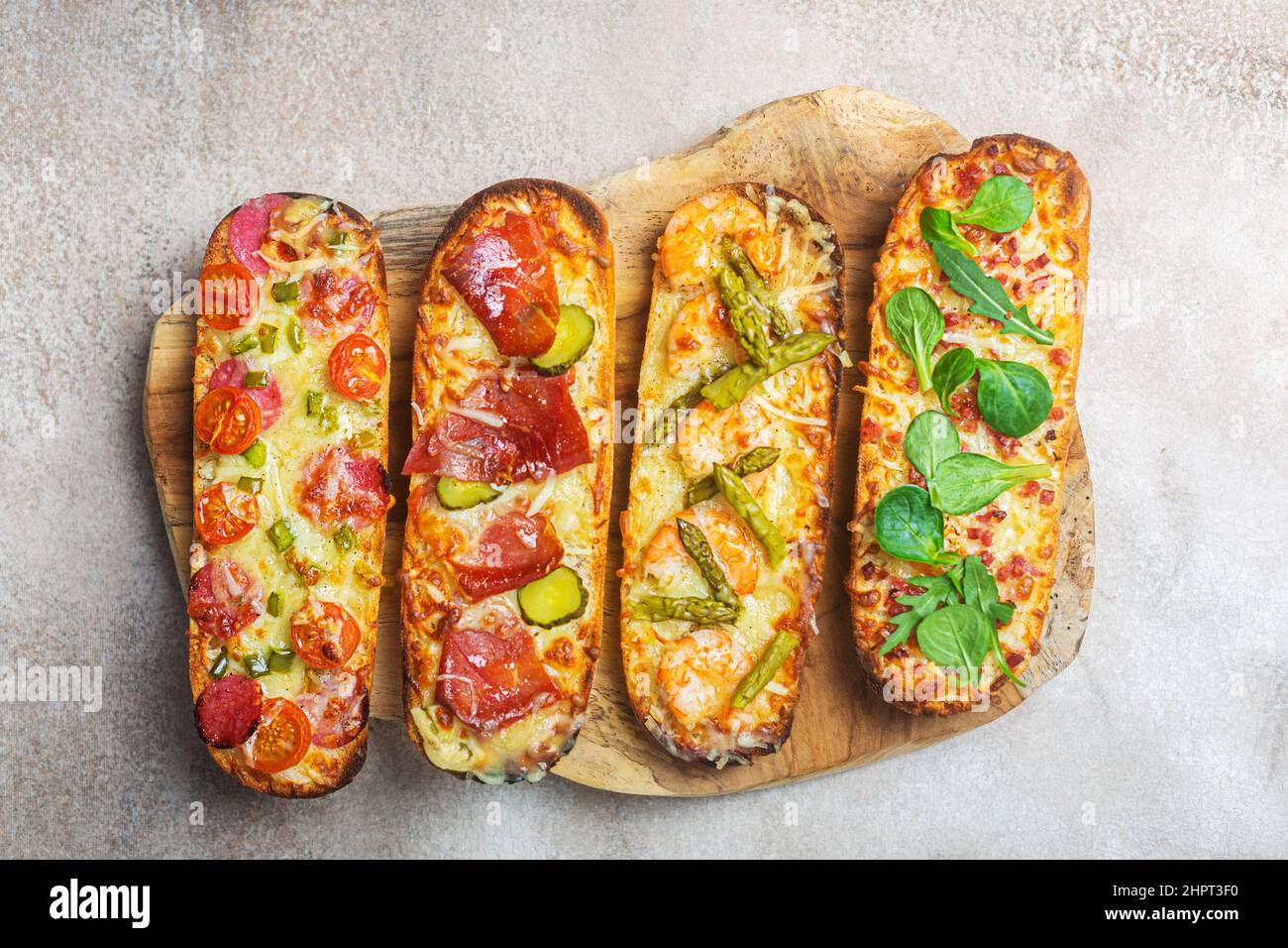 Pizzascheiben auf Brot mit Käse und Zutaten wie Salami, Prosciutto ...