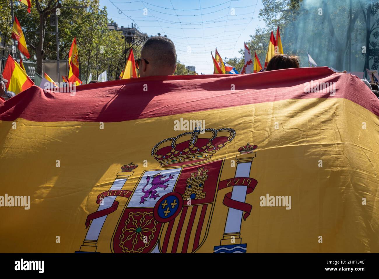 Rückansicht eines Mannes mit der spanischen Flagge während der Dia de la Hispanidad in der Gracia Avenue in Barcelona. Ein nationaler Feiertag in Spanien. Stockfoto