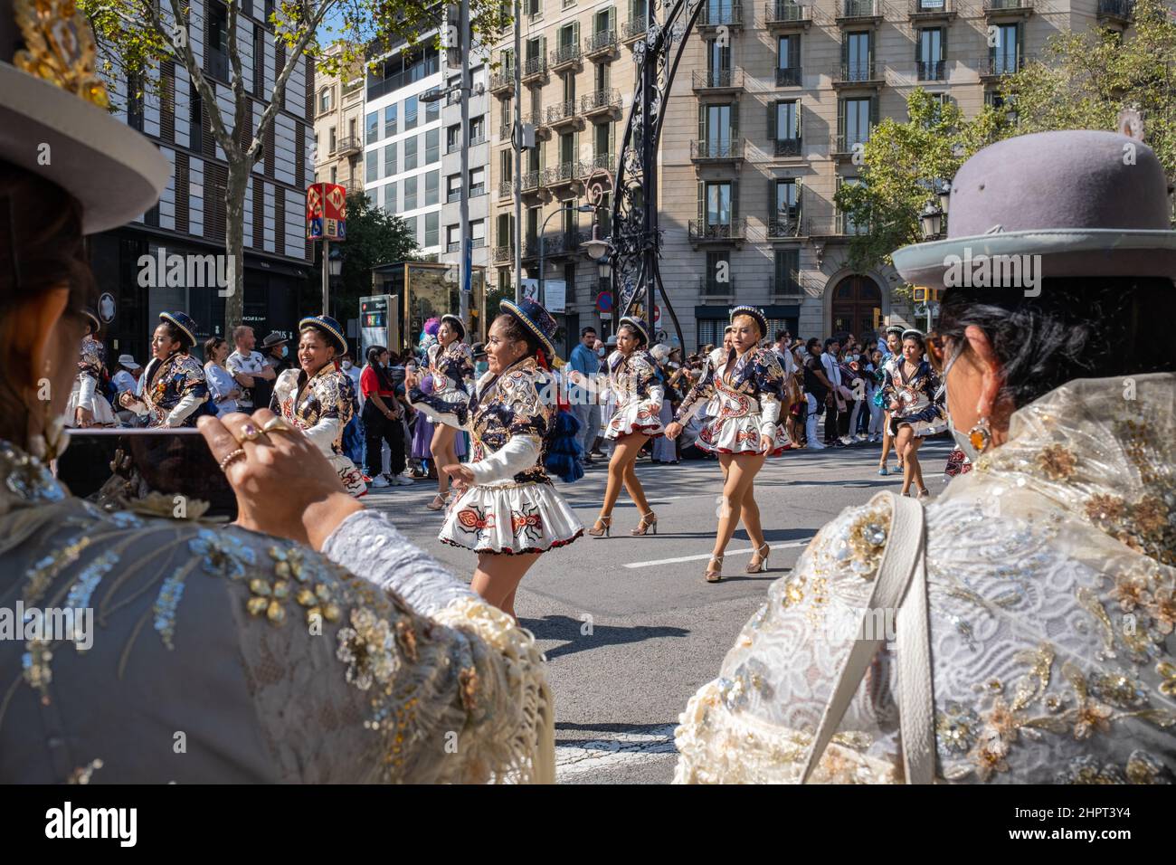 Bolivianische Frauen, die in traditionellen Outfits und Hüten gekleidet sind, treten während des Dia de la Hispanidad (Tag des hispanischen Erbes) in der Gracia Avenue in Barcelona auf Stockfoto