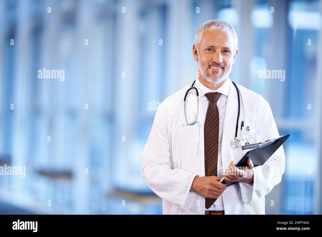 Ein Arzt zu sein ist so erfüllend. Porträt eines reifen Arztes, der eine Patientenakte in einem Krankenhausflur hält. Stockfoto