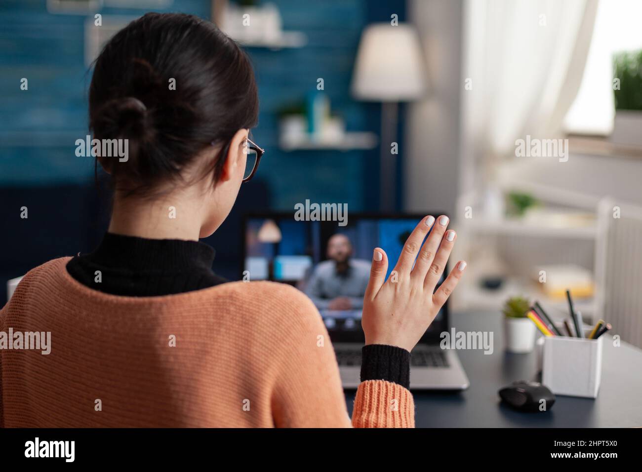 Schüler heben Hand in Online-Videocall-Klasse. Freiberufliche Mitarbeiterin mit Laptop im Heimbüro, die sich einem neuen Kunden vorstellt. Grußgeste im Videokonferenz-Interview mit dem Arbeitgeber. Stockfoto