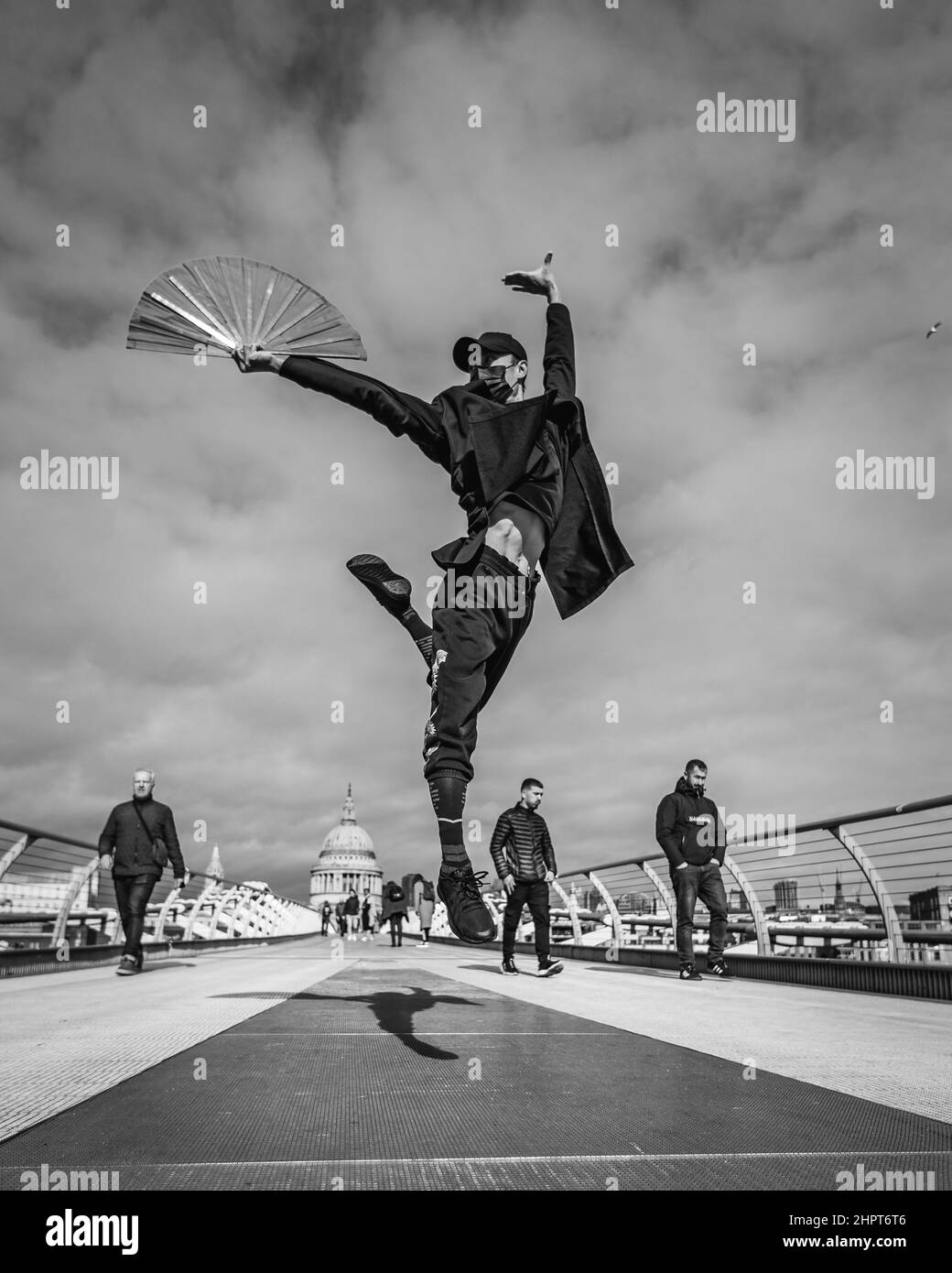 Ein schwarz-weißes Bild eines Kampfkünstlers und einer Tänzerin führt einen Ballettzug auf der Millennium Bridge in London auf. Stockfoto