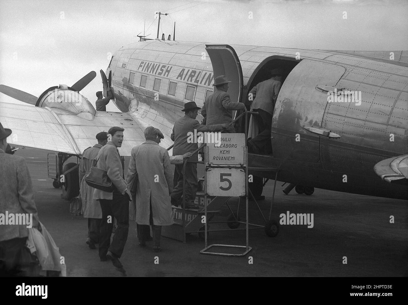 1940s, historische, männliche Passagiere, mehrere mit Regenmänteln und Hüten an Bord eines Propellers von Finnish Airlines, Douglas DC-3, am Flughafen Helsinki, Finnland. Stockfoto