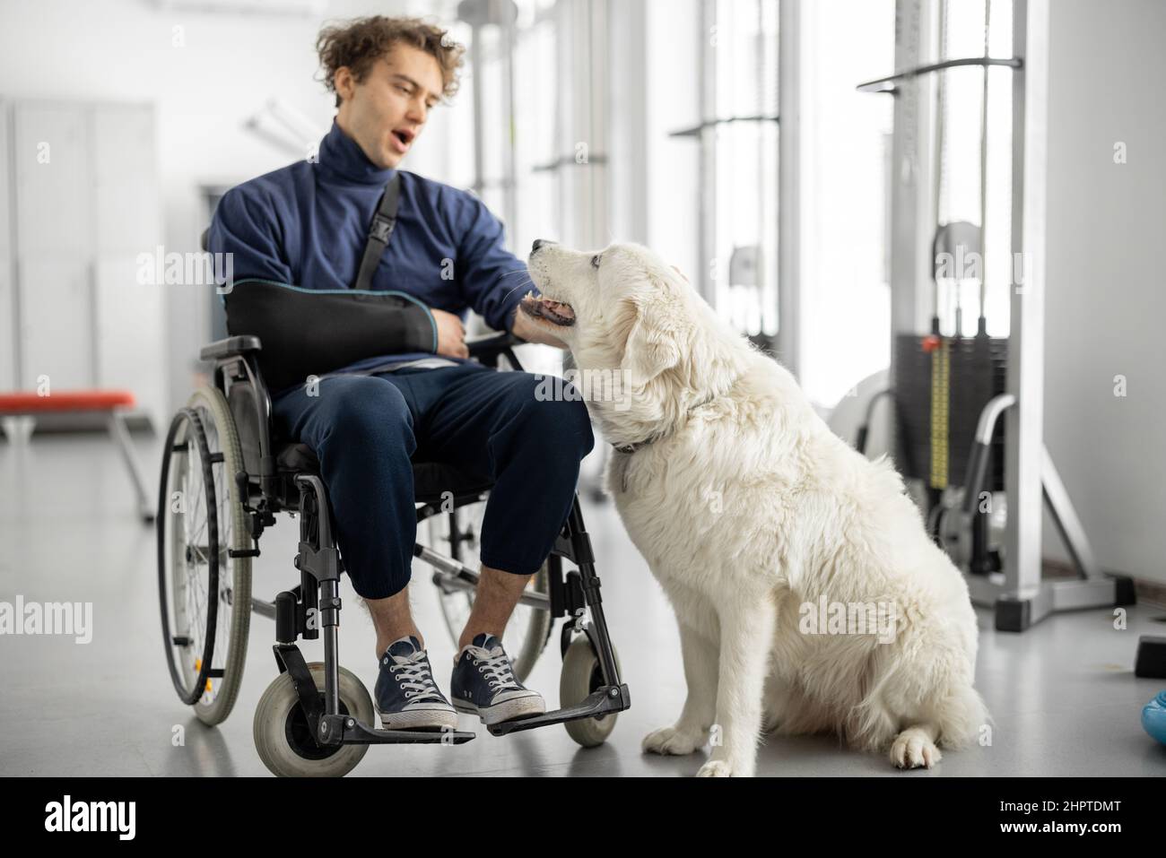 Typ mit Behinderungen im Rollstuhl mit seinem Assistenzhund im Rehabilitationszentrum Stockfoto