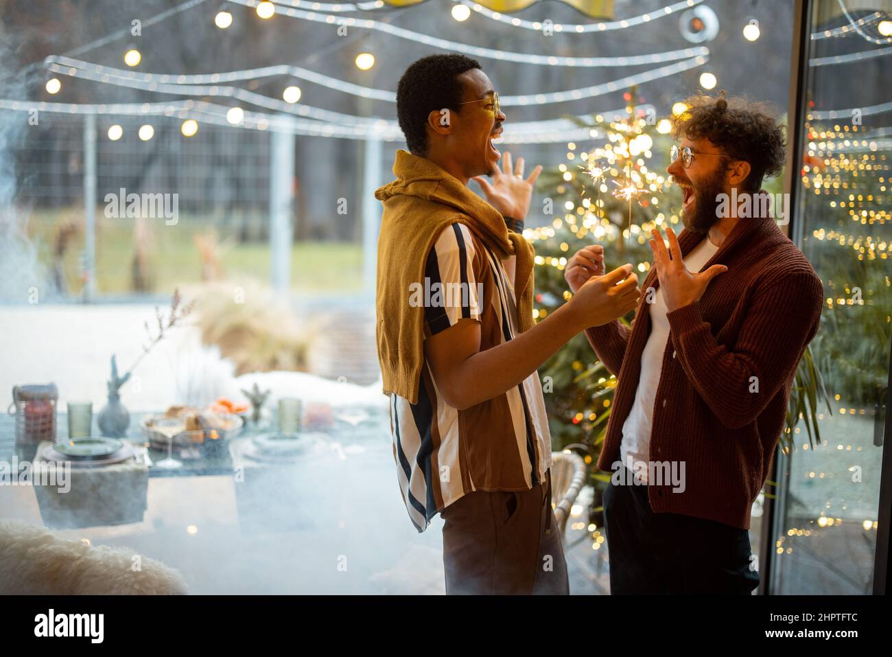Zwei männliche Freunde feiern mit Wunderkerzen im Hinterhof Stockfoto
