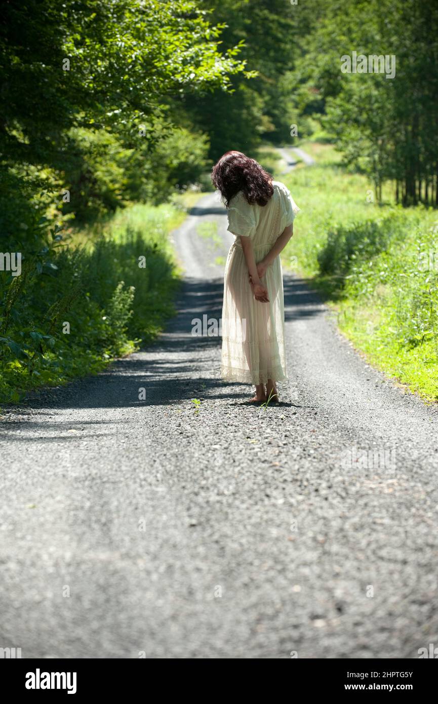 Frau in langen weißen Kleid zu Fuß auf Schotterstraße Stockfoto