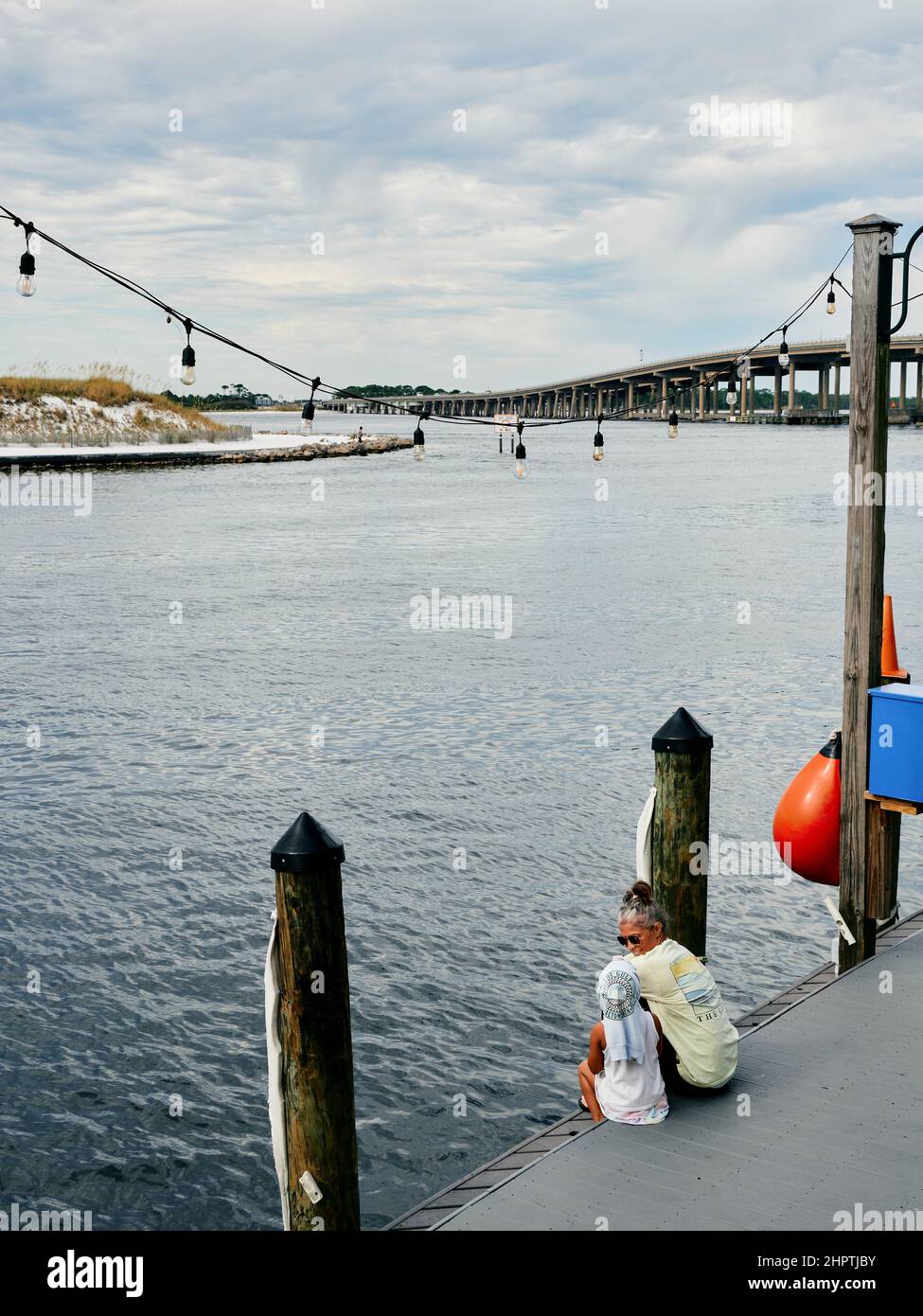 Mutter und Tochter sitzen zusammen auf einem Bootsanleger am Ufer im Hafen von Destin, Destin Florida, USA. Stockfoto