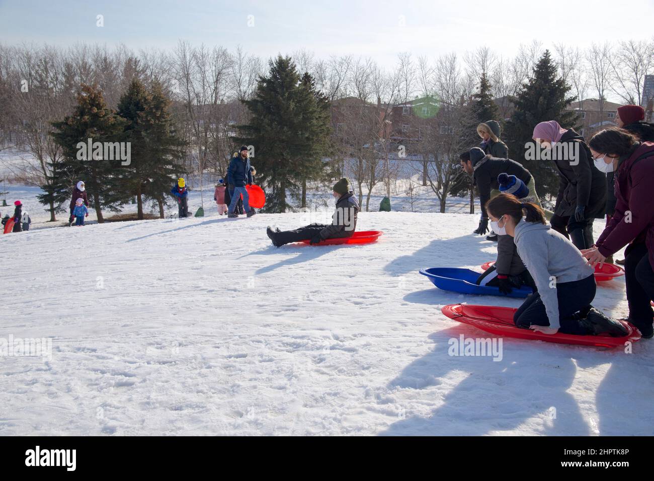 Toronto, Ontario / Canada - 02/21/2022: Familienaktivitäten unter COVID-19. Beim Rodeln im Winter tragen die Menschen eine schützende Gesichtsmaske. Stockfoto