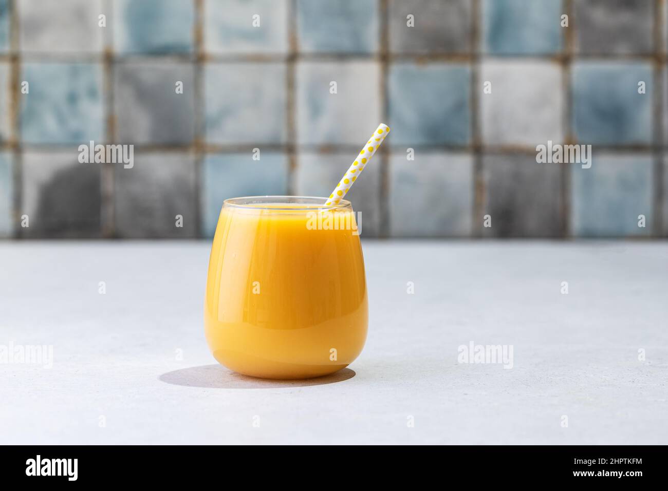 Orangensaft, Zitrus-Smoothie-Glas auf weißem Hintergrund, hartes Licht, umweltfreundlicher Cocktailstroh Stockfoto
