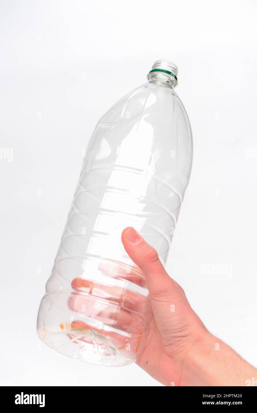 Hand hält eine Einweg-Kunststoff-Getränkeflasche bereit für das Recycling vor einem weißen Hintergrund fotografiert. Stockfoto