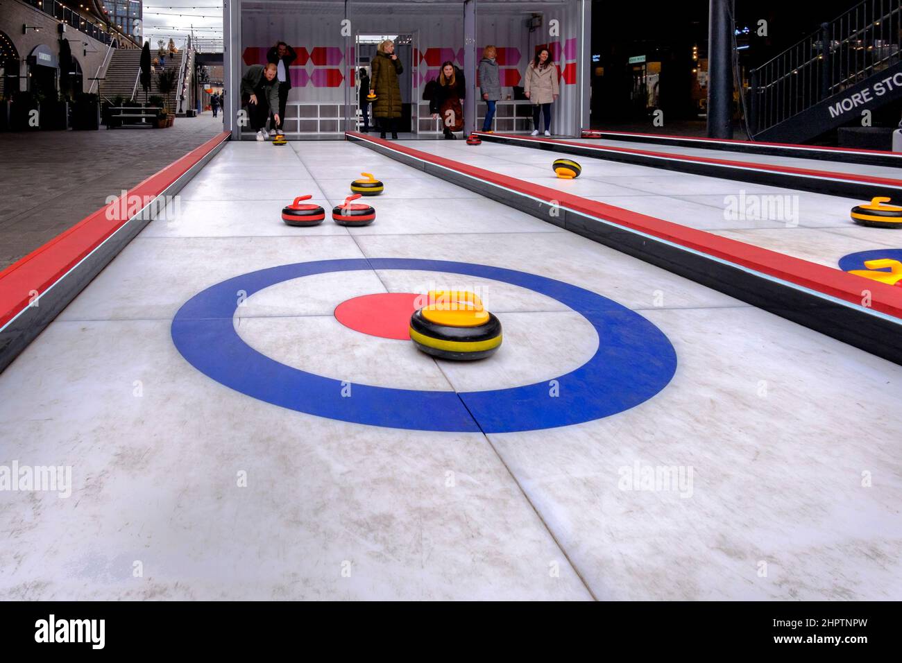 Nach dem Erfolg des Teams GB beim Curling-Event bei den Olympischen Winterspielen 2022 testen die Besucher eine künstliche Eisversion des Sports, London, Großbritannien. Stockfoto