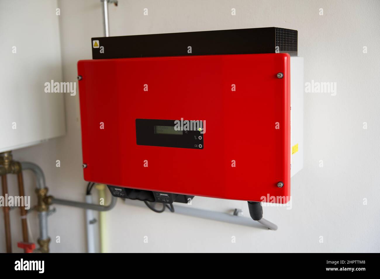 Nahaufnahme eines roten Solarwechselrichters, der an einer weißen Wand montiert ist Stockfoto
