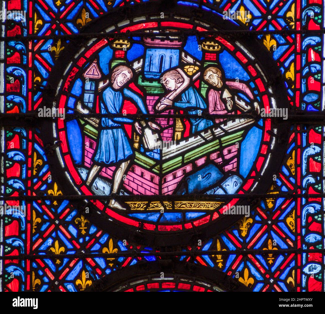 Schlossgebäude in Buntglas: Detail aus einem alten Buntglasfenster in Sainte Chapelle. Drei Männer bauen die Brüstung auf der Spitze eines Schlosses. Stockfoto